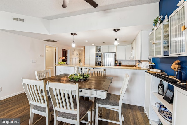 dining space with visible vents, baseboards, dark wood-style floors, and a ceiling fan