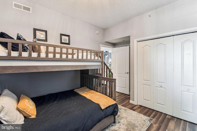 bedroom featuring visible vents, a textured ceiling, a closet, and wood finished floors