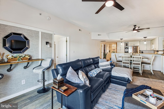 living area featuring dark wood finished floors, visible vents, baseboards, and ceiling fan