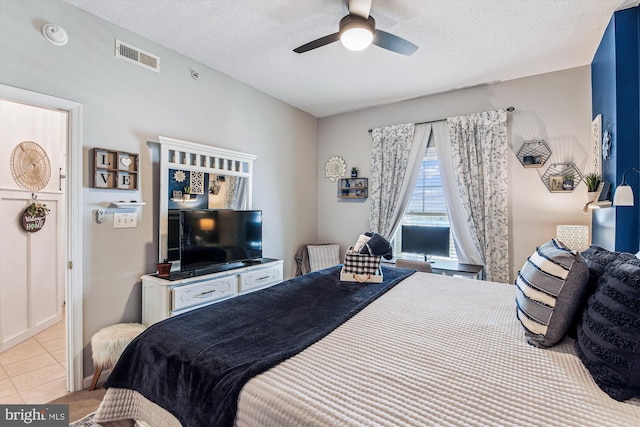 bedroom featuring light tile patterned floors, a ceiling fan, visible vents, and a textured ceiling