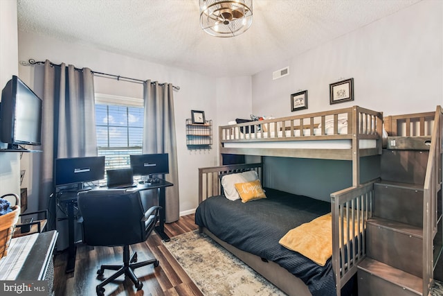 bedroom featuring visible vents, a textured ceiling, and wood finished floors