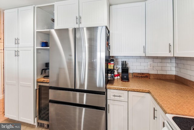 kitchen with decorative backsplash, open shelves, white cabinets, and freestanding refrigerator