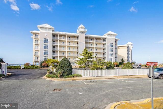 view of property with uncovered parking and fence