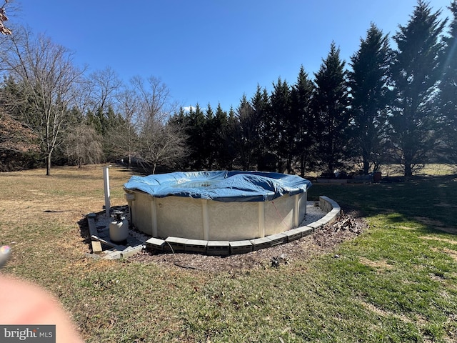 view of pool featuring a lawn and a covered pool