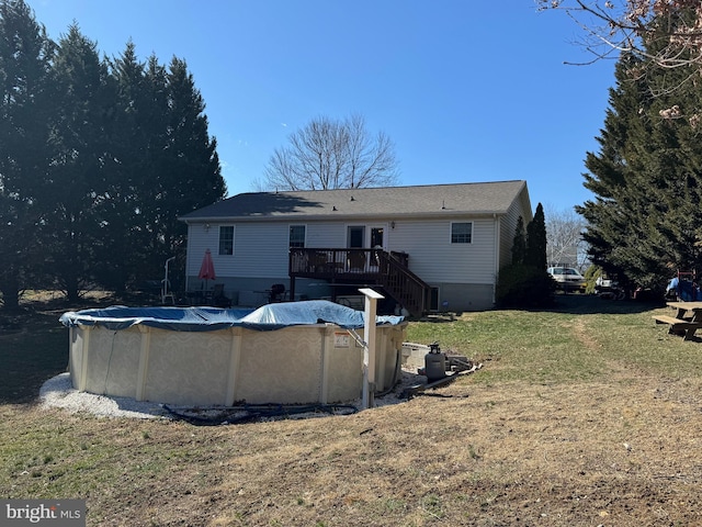 back of house with a covered pool, a yard, a deck, and stairs