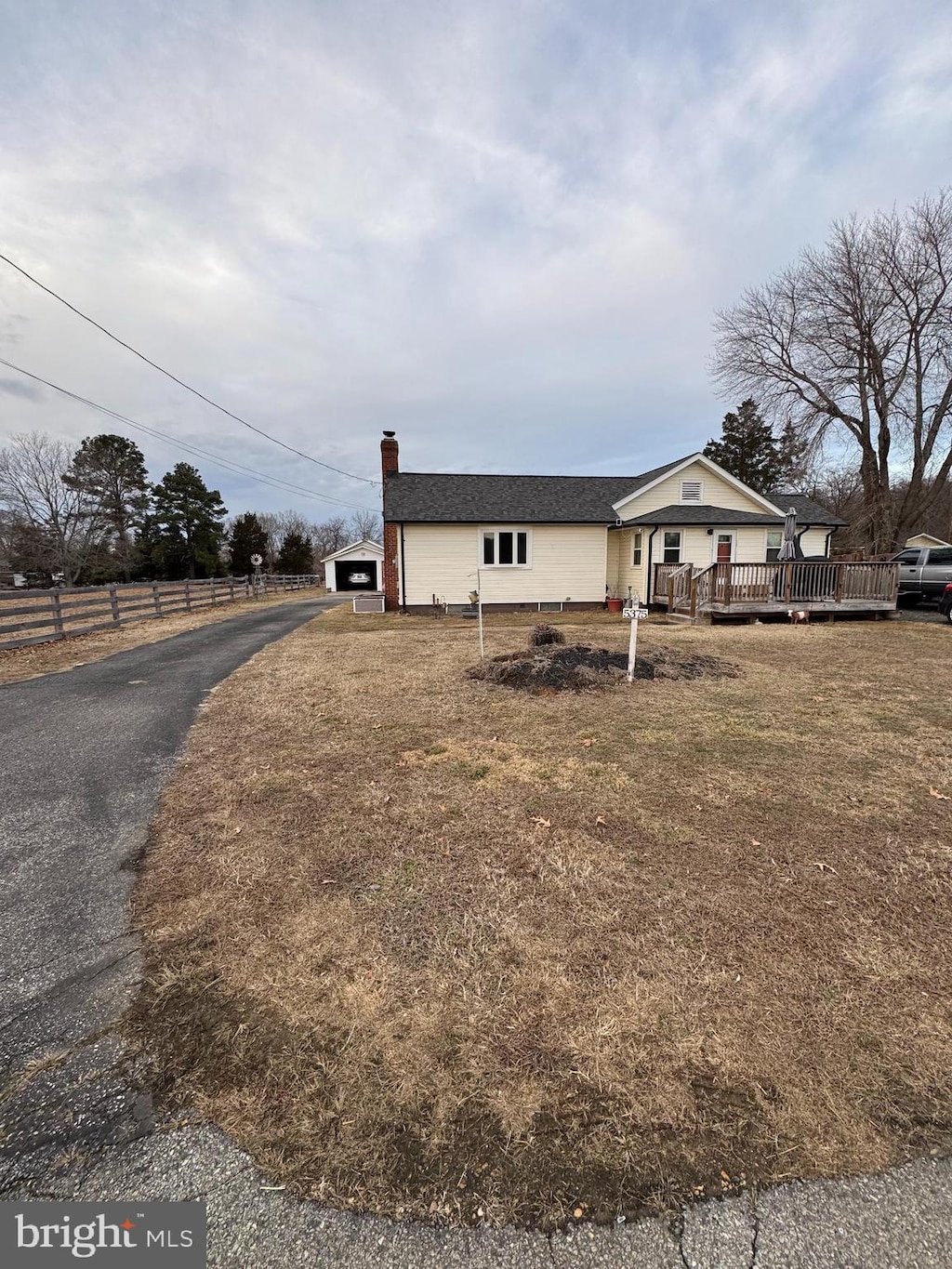 view of home's exterior featuring a lawn, a chimney, a deck, and fence