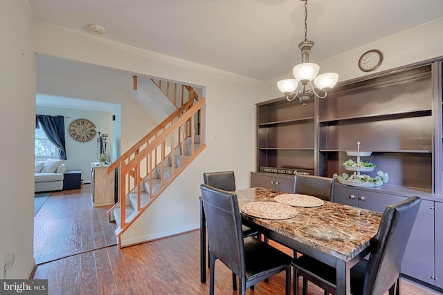 dining space with stairway, wood finished floors, and a notable chandelier