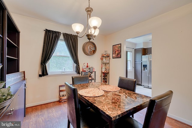dining area with an inviting chandelier, light wood-style flooring, and baseboards