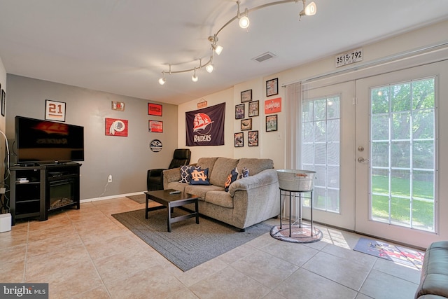 living area with light tile patterned floors, visible vents, french doors, and baseboards