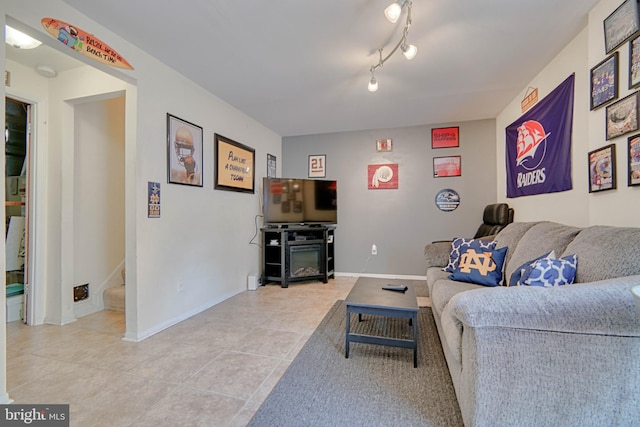 living room featuring baseboards, stairway, and light tile patterned floors
