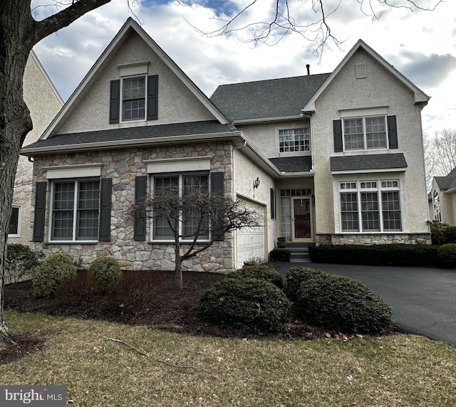 traditional home with stone siding, aphalt driveway, and stucco siding