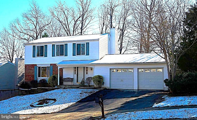 traditional home featuring aphalt driveway, covered porch, a garage, and a chimney