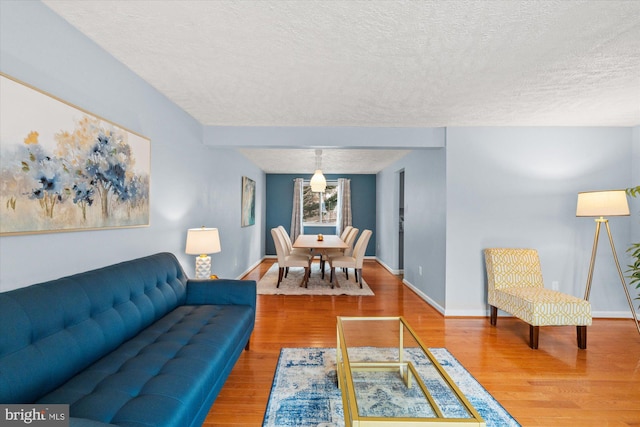 living room with a textured ceiling, baseboards, and wood finished floors