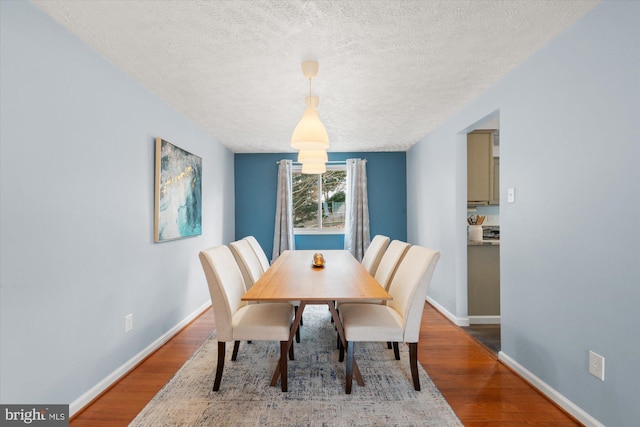 dining room with wood finished floors, baseboards, and a textured ceiling