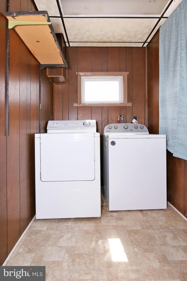 clothes washing area with washer and dryer, laundry area, and wood walls