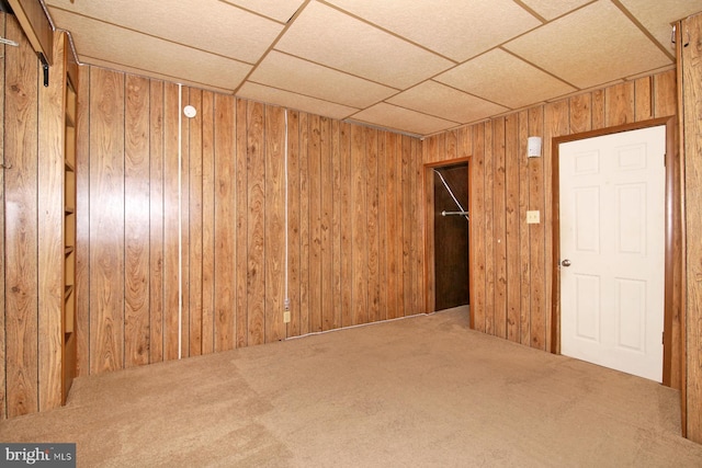 interior space featuring a paneled ceiling and wood walls