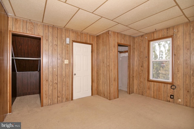 unfurnished bedroom with a closet, wooden walls, and carpet floors