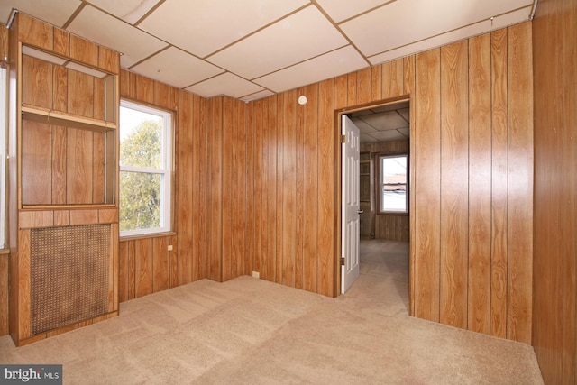 carpeted spare room with a drop ceiling and wood walls