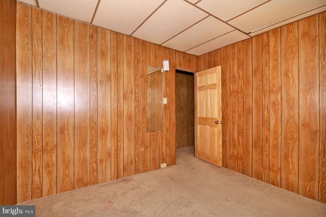 carpeted empty room featuring wooden walls