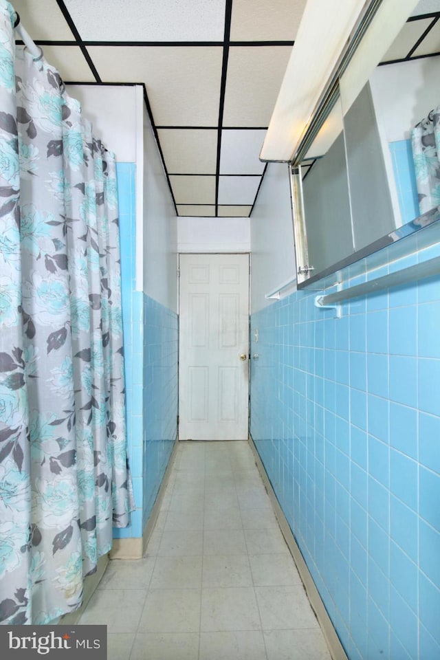 full bath with tile patterned flooring, tile walls, and wainscoting