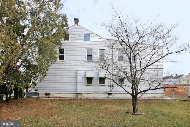 view of side of property featuring a yard and a chimney