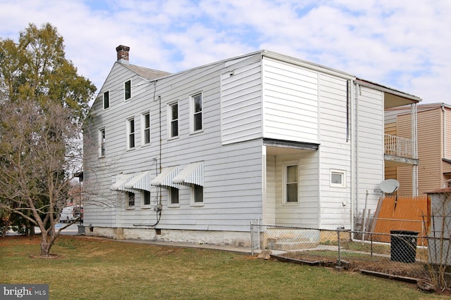 view of side of home featuring a lawn and fence