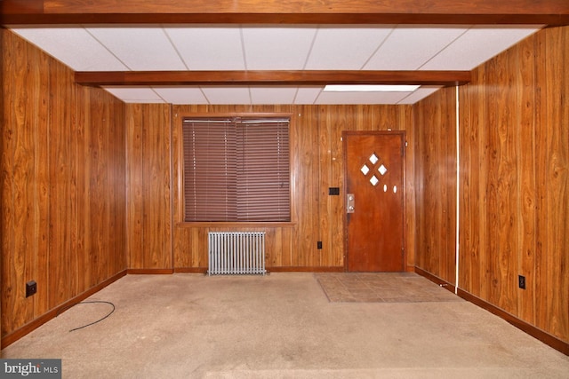 entryway with carpet floors, radiator, and wood walls