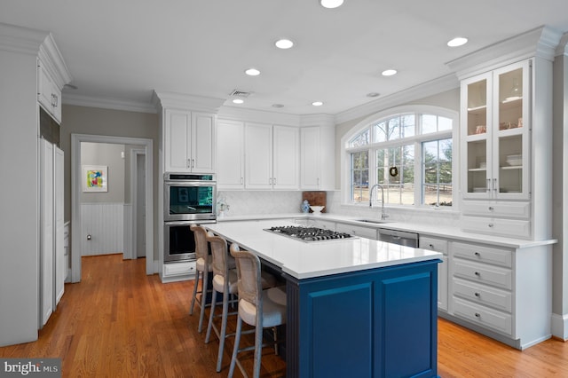 kitchen with crown molding, white cabinets, appliances with stainless steel finishes, and a sink