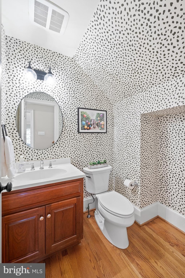 bathroom featuring visible vents, toilet, vanity, and wood finished floors