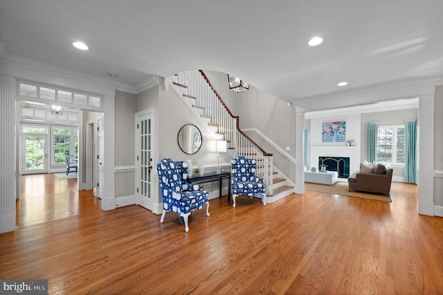 foyer featuring wood finished floors, a fireplace, stairs, french doors, and crown molding