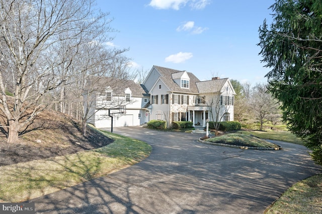 view of front facade with driveway, a chimney, and a balcony