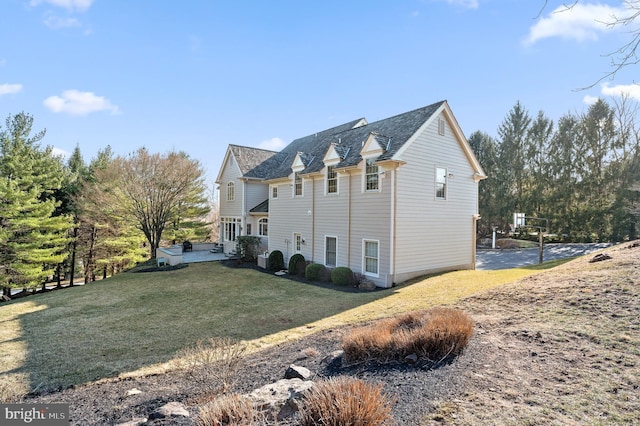 view of side of property featuring a patio area and a lawn