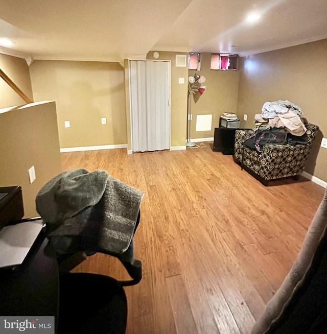 living area with ornamental molding, wood finished floors, and baseboards