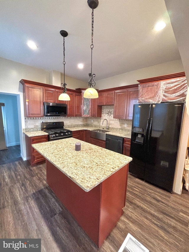 kitchen featuring dark wood-style flooring, black appliances, pendant lighting, tasteful backsplash, and a center island