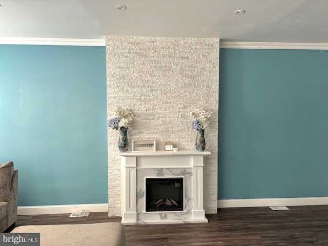 unfurnished living room with baseboards, wood finished floors, ornamental molding, and a fireplace