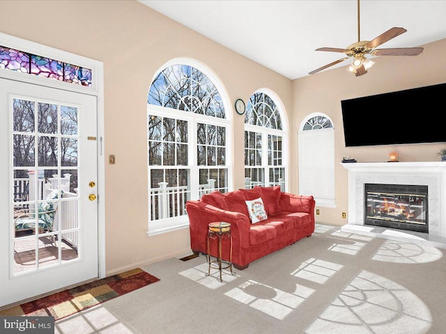 living room with a ceiling fan, baseboards, carpet, and a high end fireplace