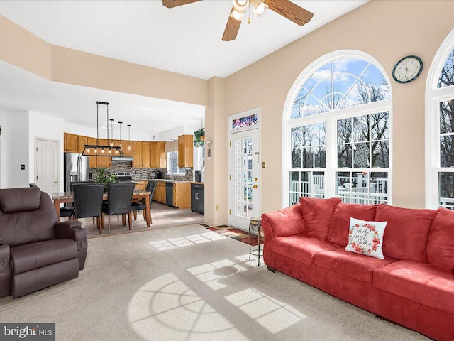 living area with a ceiling fan and light carpet