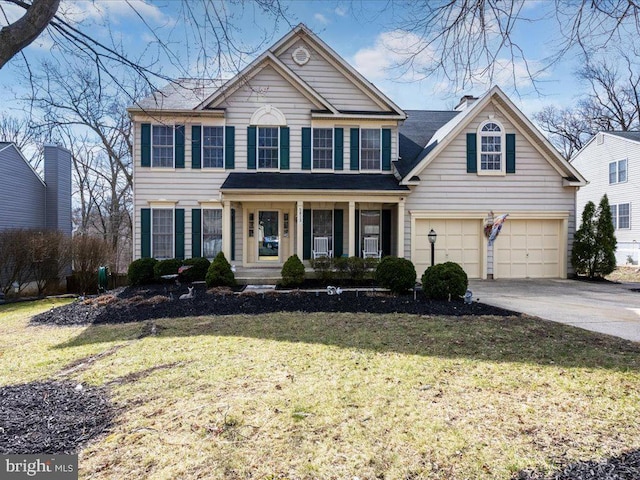 view of front of property featuring a garage, driveway, a chimney, and a front yard