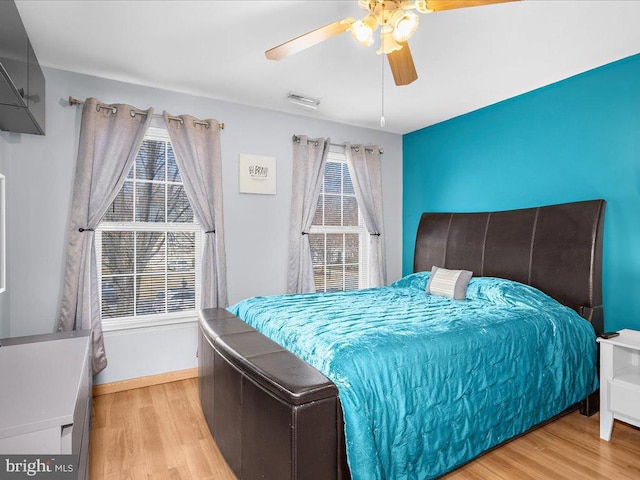 bedroom featuring ceiling fan, visible vents, baseboards, and wood finished floors