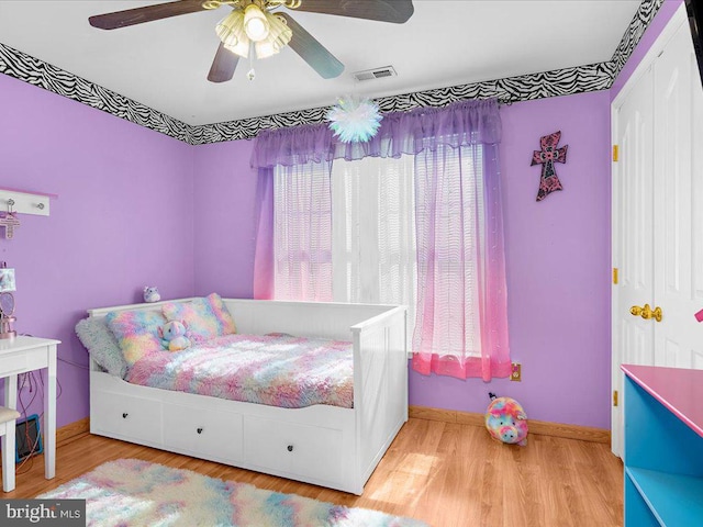 bedroom with visible vents, a ceiling fan, baseboards, and wood finished floors