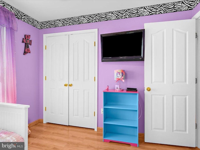 bedroom with baseboards, light wood-type flooring, and a closet