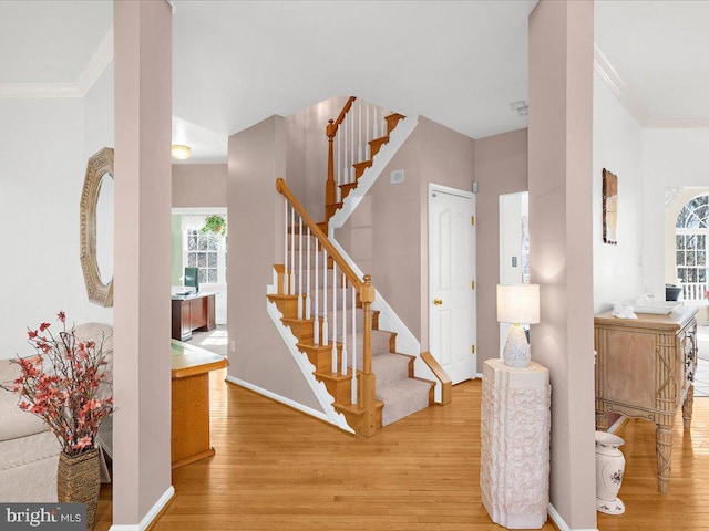 stairway featuring baseboards, wood finished floors, and ornamental molding