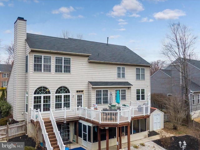 back of house featuring stairway, a chimney, an outdoor structure, a storage unit, and a deck