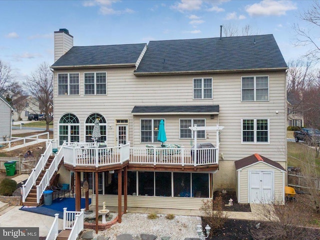 rear view of property featuring stairway, a shed, a chimney, a deck, and an outbuilding