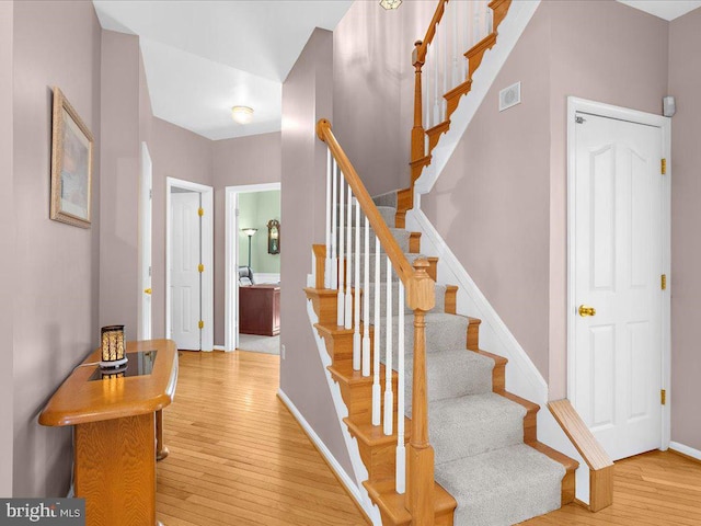 stairway featuring visible vents, wood-type flooring, and baseboards