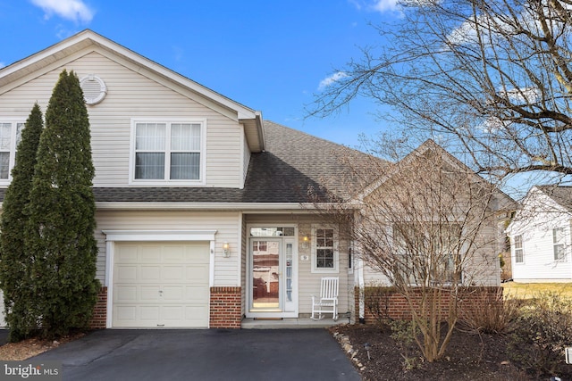 traditional home with a garage, brick siding, driveway, and a shingled roof