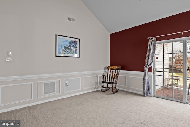 living area with visible vents, carpet flooring, a decorative wall, and vaulted ceiling