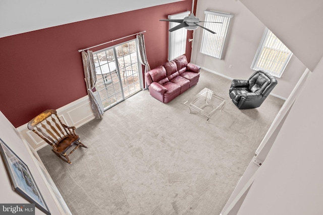 living area with a wainscoted wall, carpet floors, ceiling fan, and vaulted ceiling