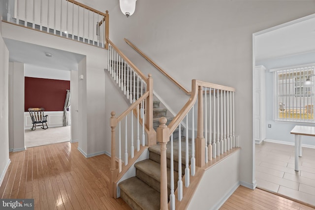 staircase featuring a high ceiling, baseboards, and wood-type flooring