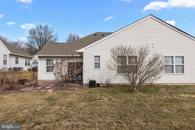 rear view of property featuring a patio, a lawn, and a shingled roof